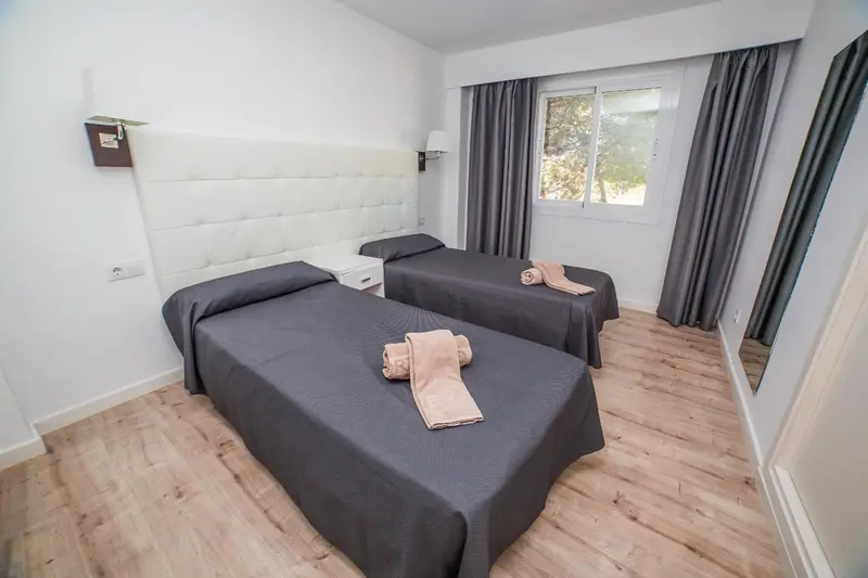 Une chambre avec deux lits simples et une décoration sobre.