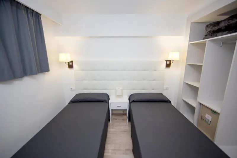 Une chambre avec deux lits simples et une décoration sobre.