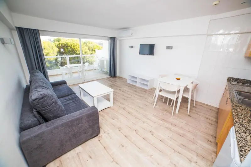 Espace de vie lumineux avec canapé, table et cuisine équipée.