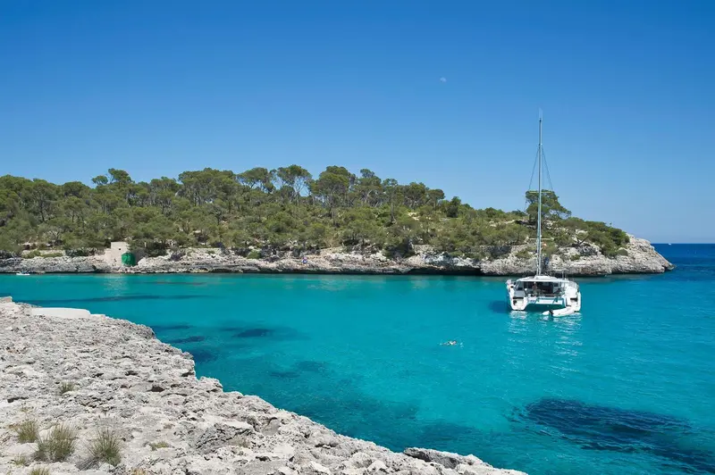 Une crique abritée avec un catamaran amarré dans une eau turquoise.