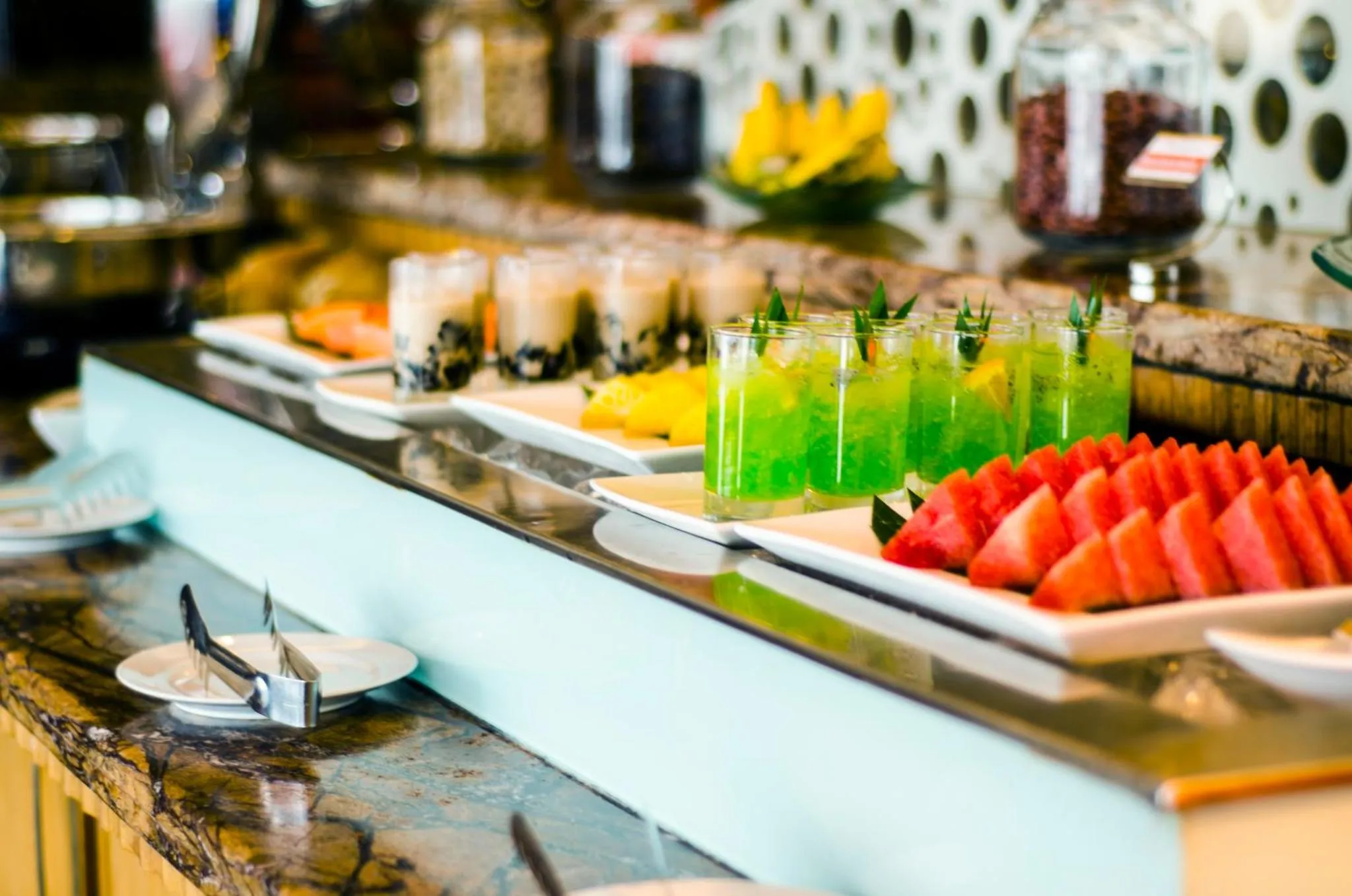 Un buffet propose une variété de fruits et de boissons colorées.