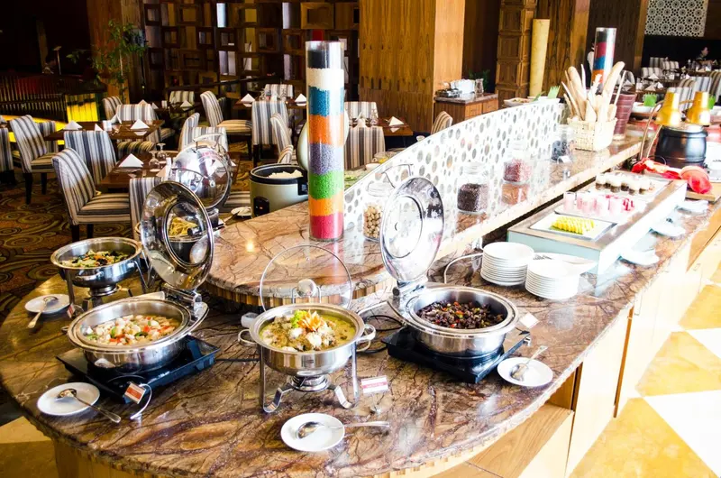 Un buffet propose une variété de plats et de desserts dans une salle lumineuse.
