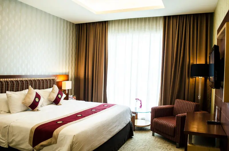 Une chambre d'hôtel avec un grand lit et un fauteuil près d'une fenêtre.