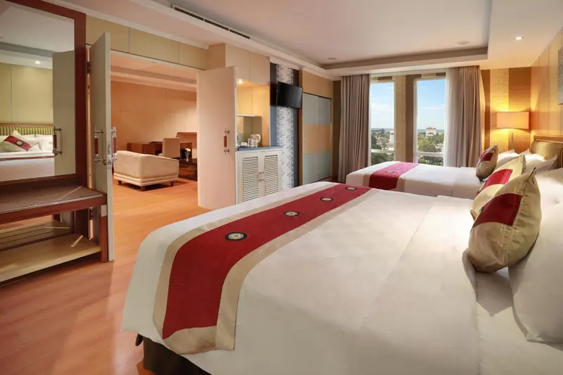Chambre lumineuse avec deux lits et un espace salon.