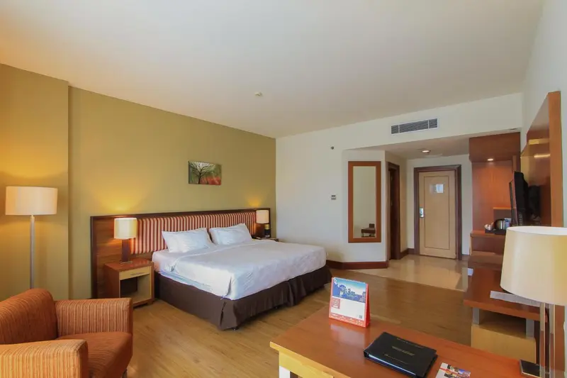 Une chambre lumineuse avec un grand lit et un coin salon.