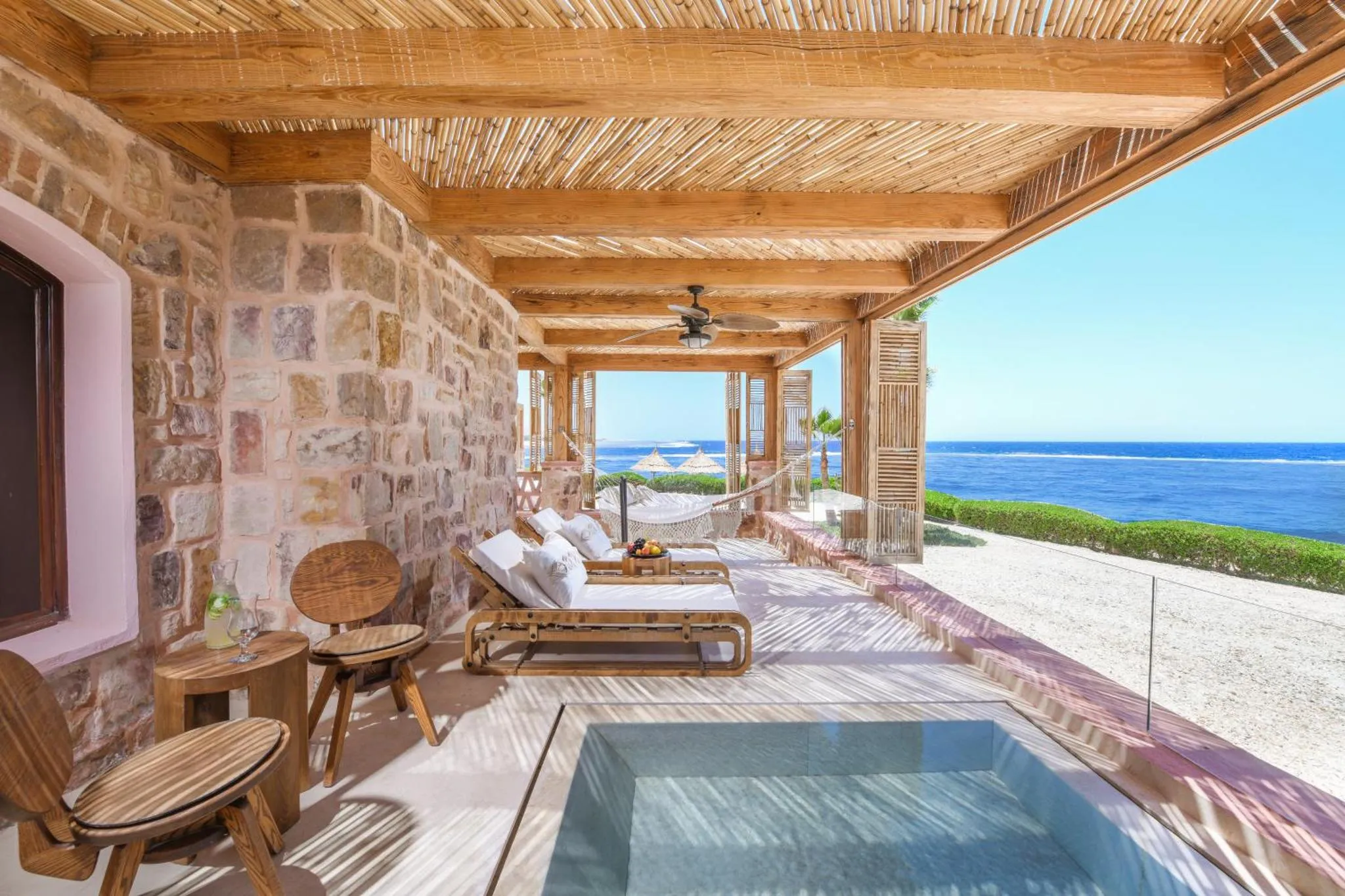 Terrasse ombragée avec mobilier de détente et vue sur la mer.