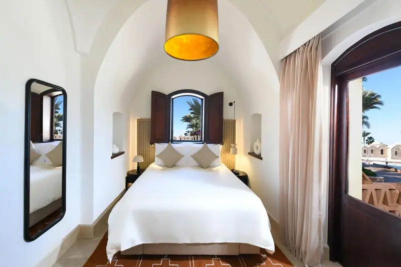 Une chambre lumineuse avec un grand lit et un miroir mural.