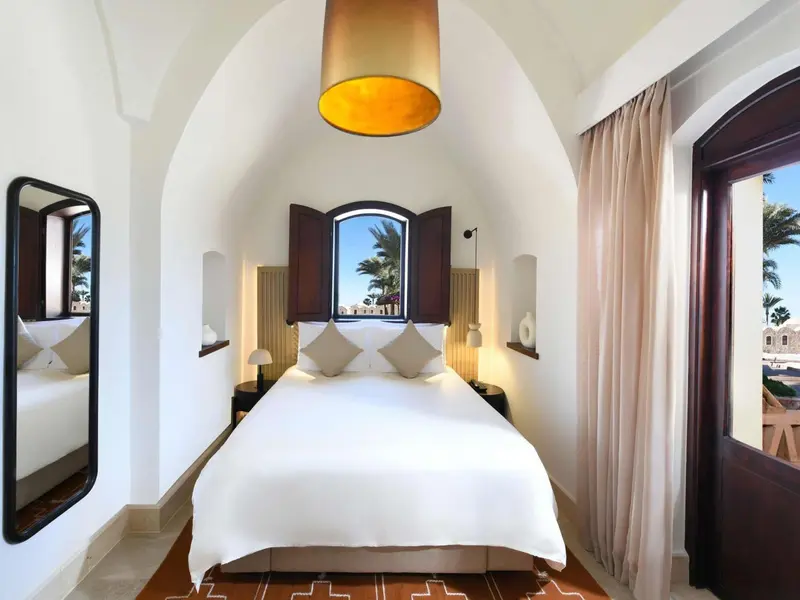 Une chambre lumineuse avec un lit blanc et un éclairage chaleureux.