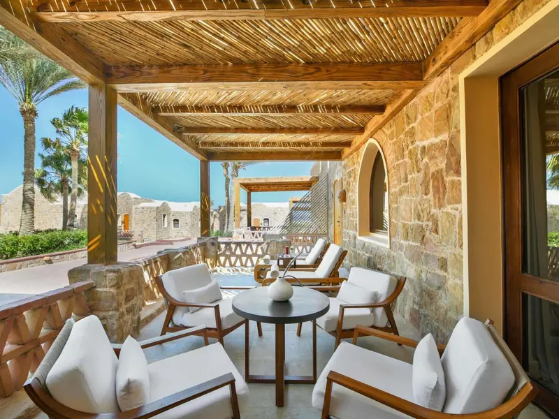 Espace extérieur ombragé avec mobilier de détente et vue sur la mer.