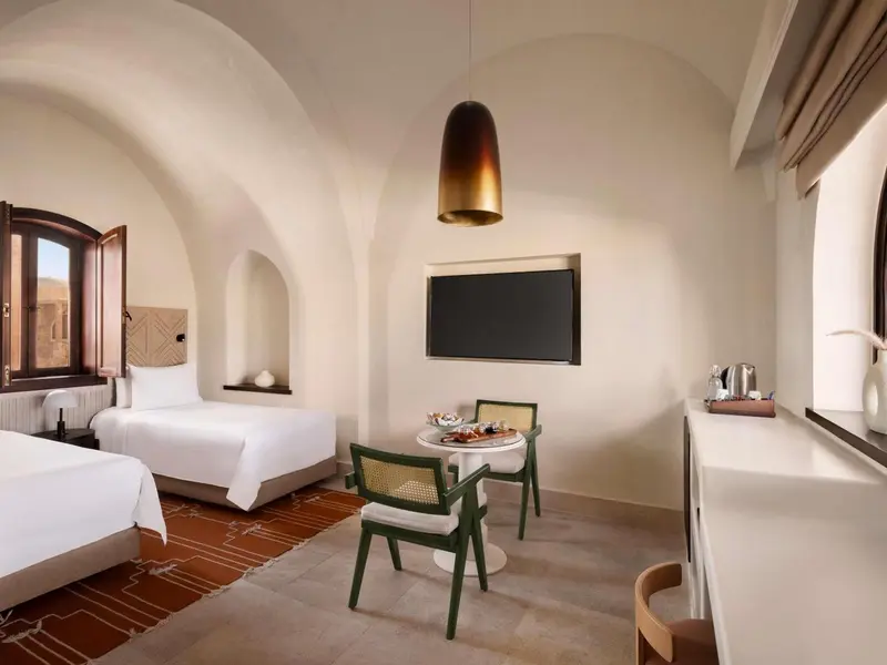 Une chambre lumineuse avec deux lits simples et un coin repas.