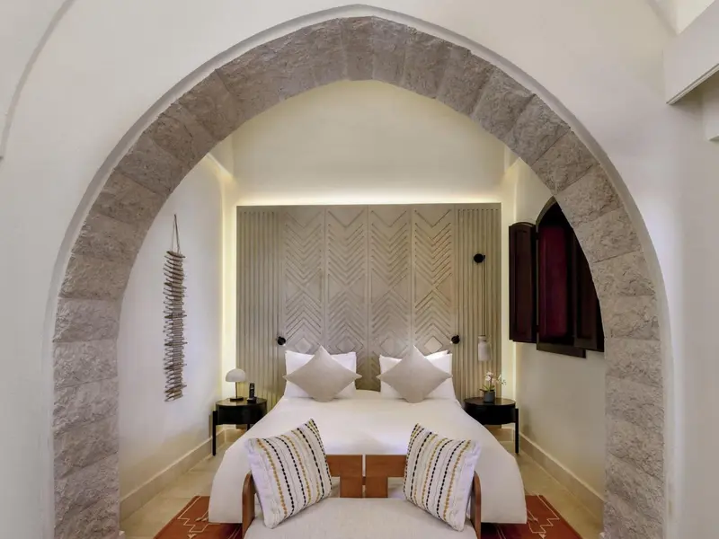 Une chambre à coucher lumineuse avec un lit à baldaquin et des murs en pierre.