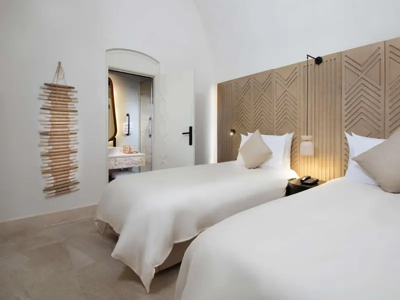 Une chambre lumineuse avec deux lits simples et une décoration murale en bois.