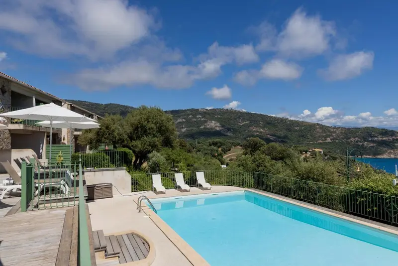 Transats et piscine au bord d'une terrasse ensoleillée avec vue sur les collines.