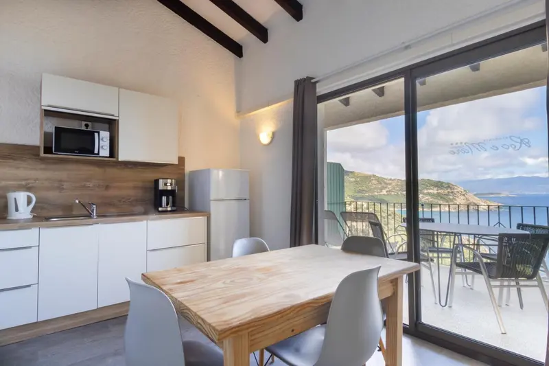 Une cuisine ouverte sur une salle à manger lumineuse donnant sur une terrasse avec vue sur la mer.