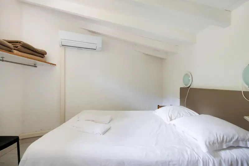 Une chambre lumineuse avec un lit simple et un climatiseur mural.