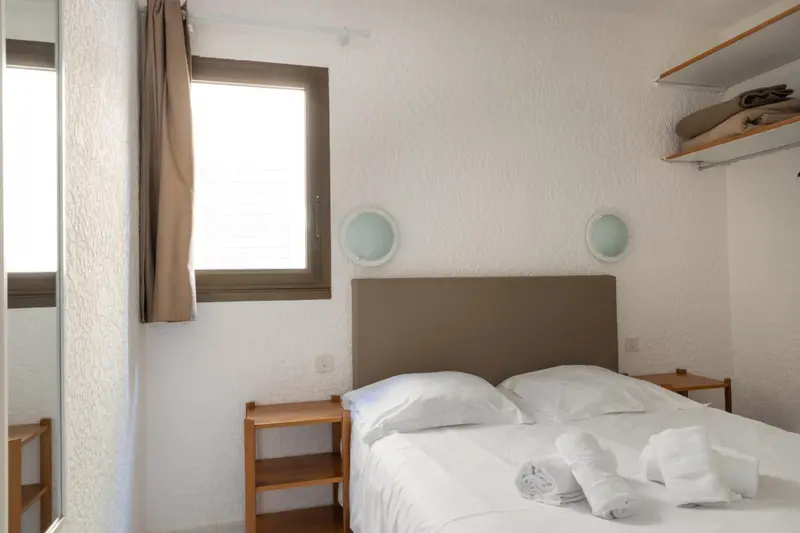 Une chambre lumineuse avec un lit double et une fenêtre.