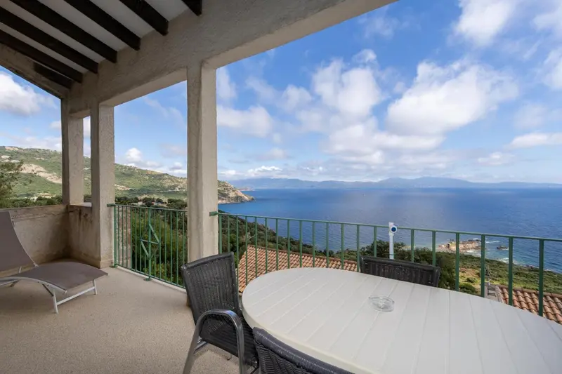 Terrasse avec mobilier d'extérieur donnant sur une vue panoramique sur la mer et les collines.