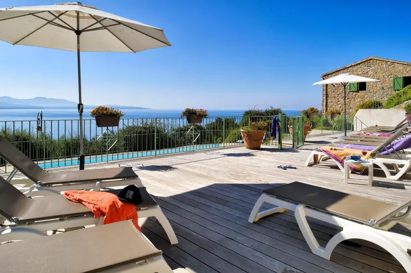 Terrasse en bois avec transats et vue sur la mer.