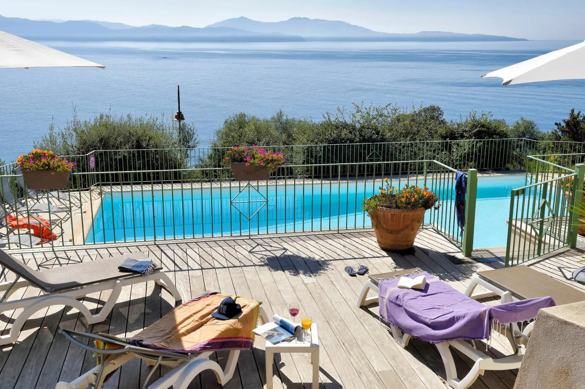 Terrasse avec transats et piscine face à la mer.