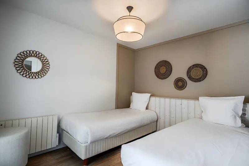 Une chambre lumineuse avec deux lits simples et des décorations murales.