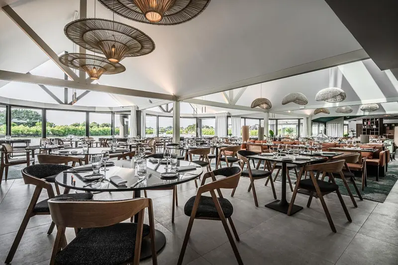 Une salle lumineuse avec des tables dressées pour un repas.