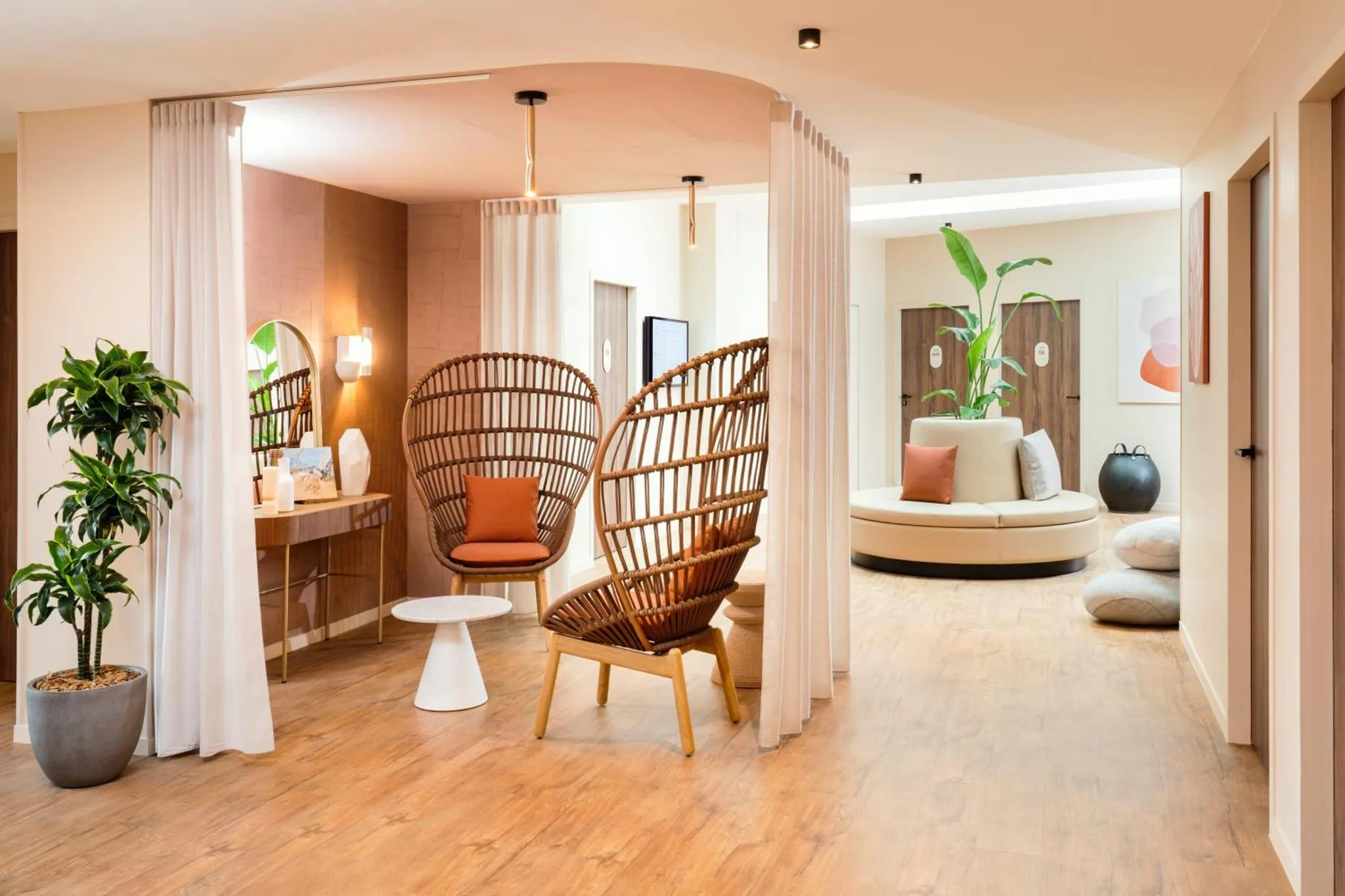 Espace de détente intérieur avec fauteuils en osier et canapé circulaire.