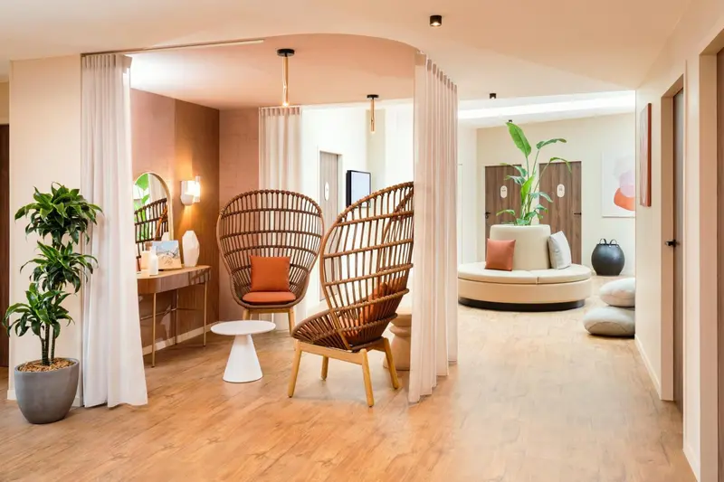 Espace de détente intérieur avec fauteuils en osier et canapé circulaire.