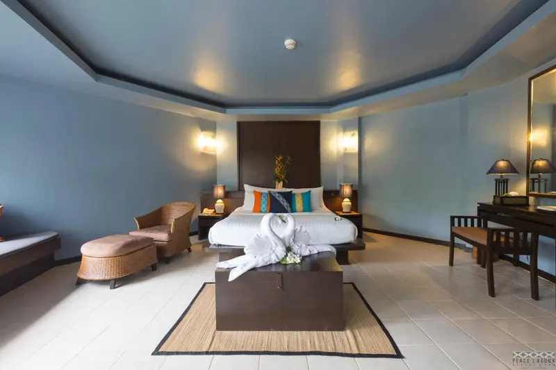 Chambre spacieuse avec un lit double décoré de serviettes en forme de cygnes.