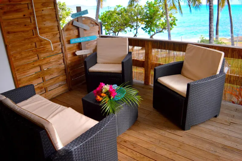 Mobilier de jardin en rotin sur une terrasse en bois avec vue sur la mer.
