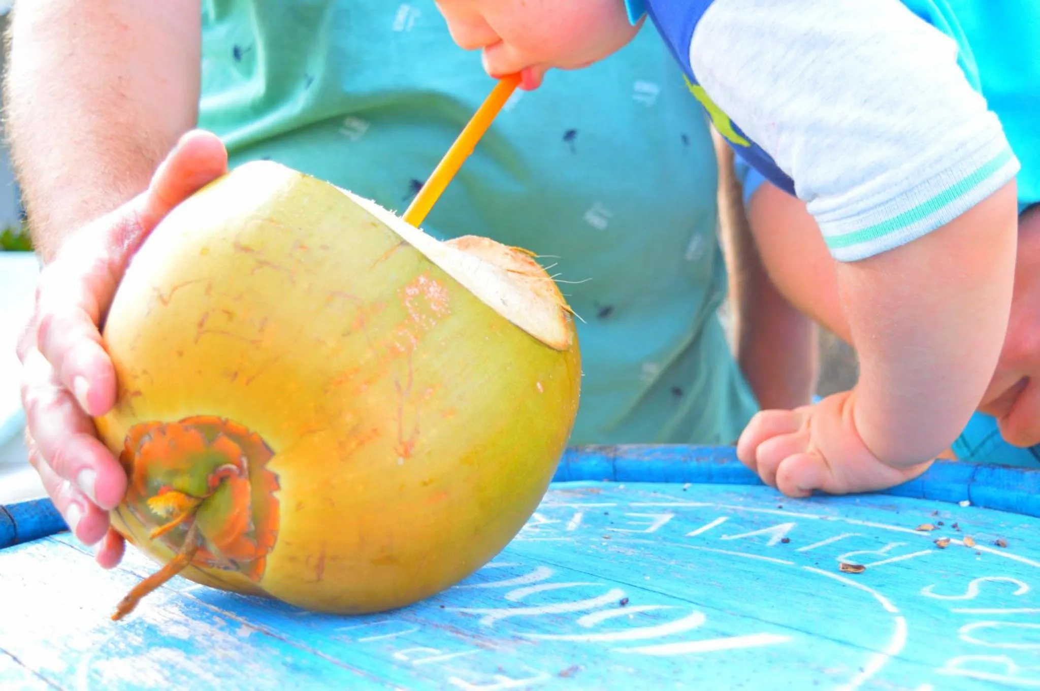 Un enfant boit dans une noix de coco fraîche.