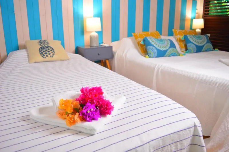 Deux lits simples décorés de coussins colorés dans une chambre lumineuse.