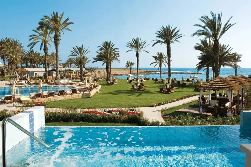 Vue aérienne d'un complexe hôtelier avec piscine et végétation luxuriante face à la mer.