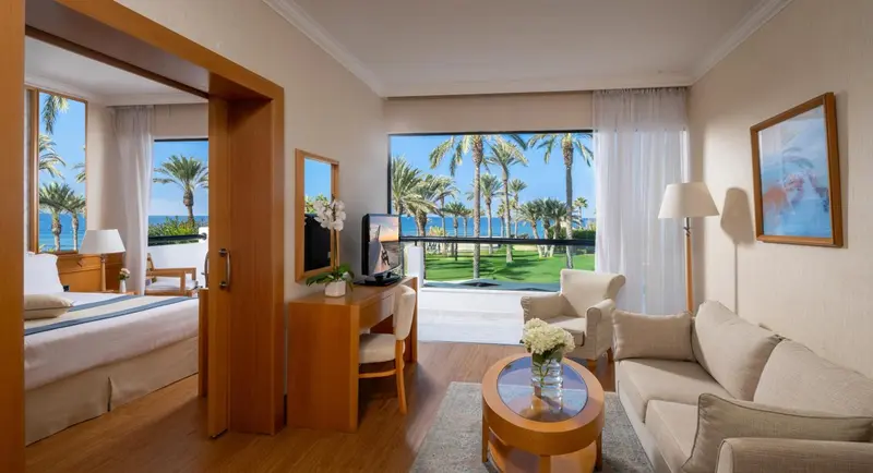 Une pièce lumineuse donne sur une vue tropicale avec des palmiers et la mer.