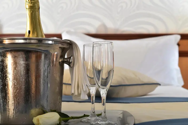 Une bouteille de champagne et deux flûtes sont posées sur un lit.