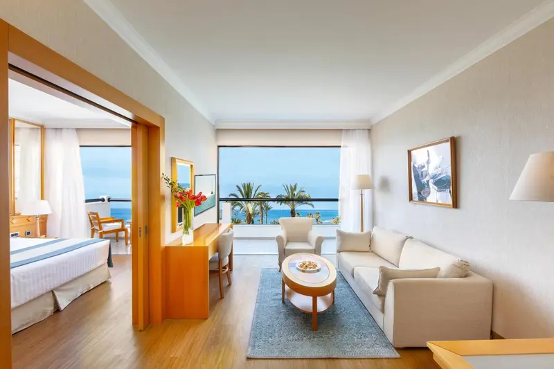 Espace de vie lumineux avec canapé, table basse et vue sur la mer.