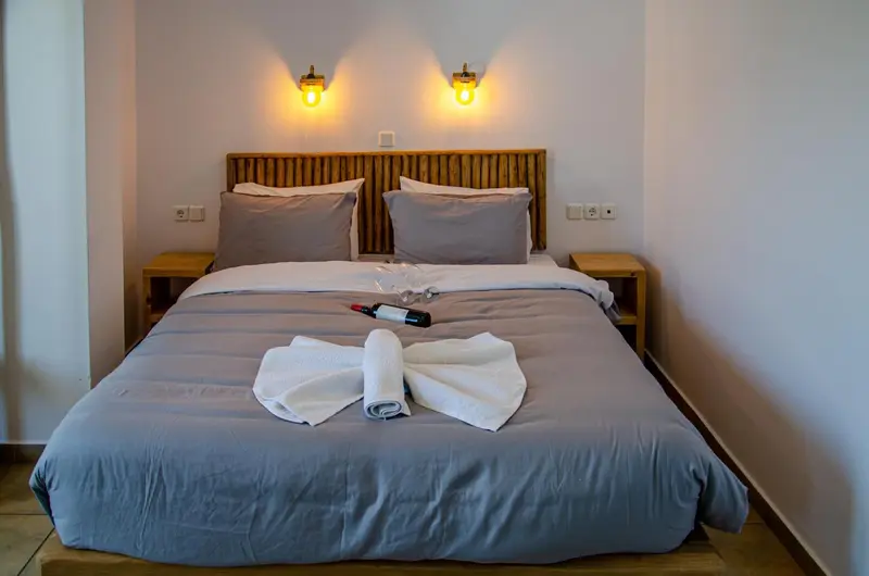 Une chambre avec un grand lit recouvert d'une couette grise et de deux oreillers.