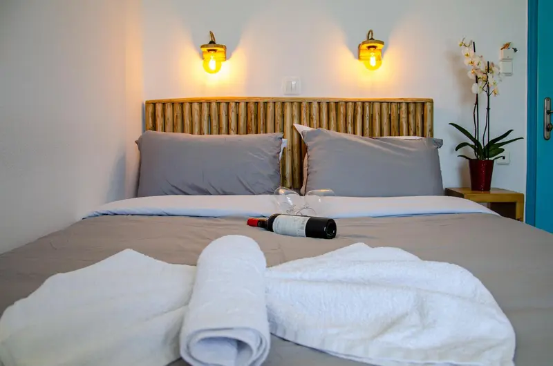 Un lit double avec une tête de lit en bambou et des oreillers gris dans une chambre.