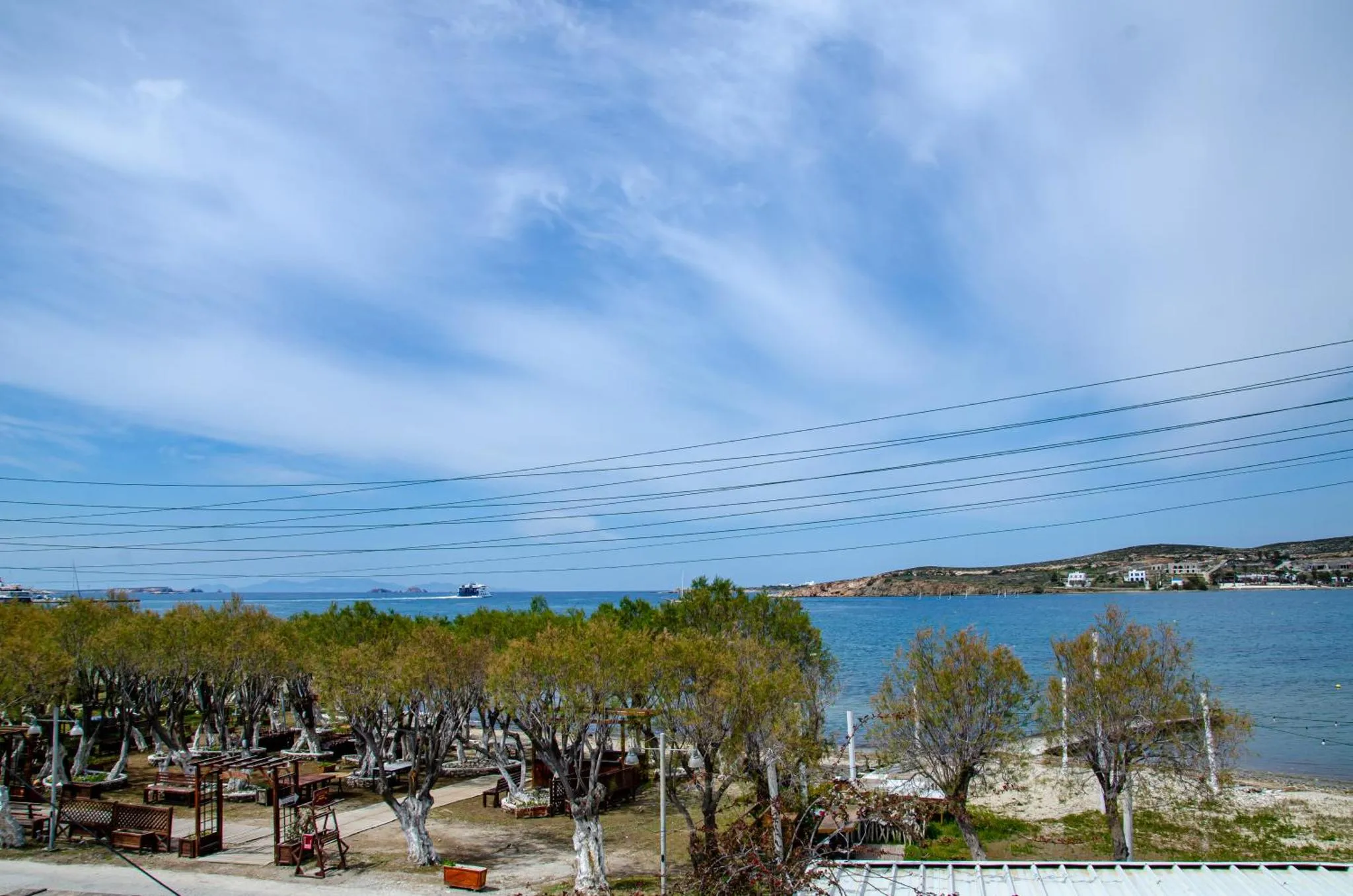 Vue sur la mer et la côte depuis une terrasse ombragée.