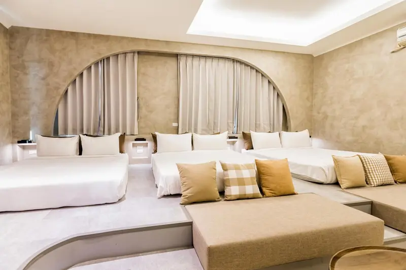 Une chambre lumineuse avec de larges lits blancs et des coussins décoratifs.