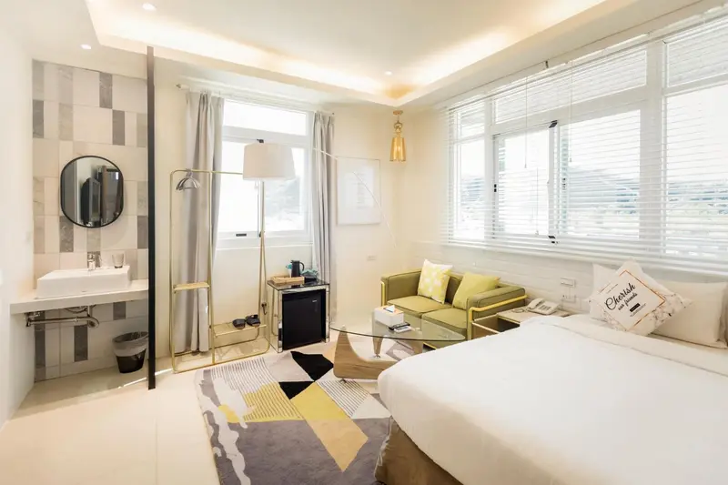 Une chambre lumineuse avec un coin salon et une salle de bain ouverte.