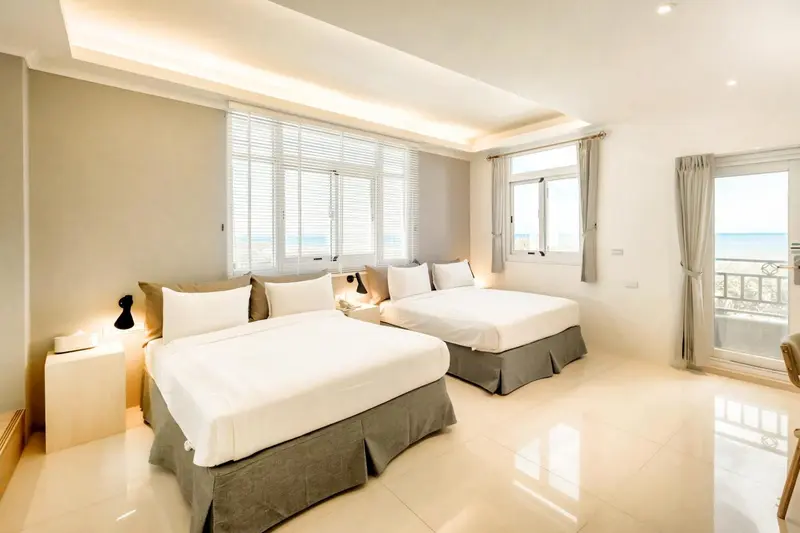 Chambre lumineuse avec deux lits simples et vue sur la mer.