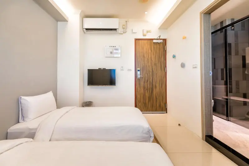 Une chambre lumineuse avec deux lits simples et un téléviseur mural.