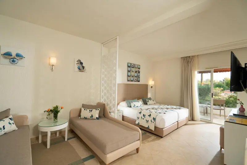 Une chambre lumineuse avec un canapé et un lit double donnant sur une terrasse.