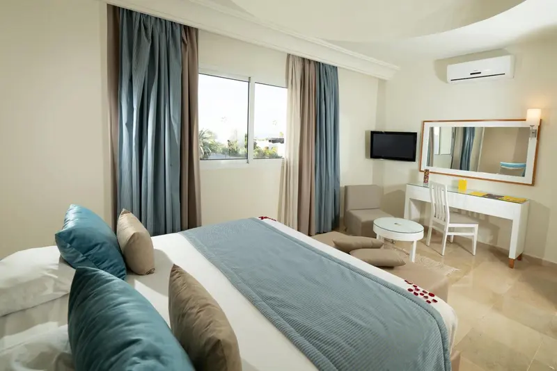 Une chambre lumineuse avec un grand lit et un coin coiffeuse.