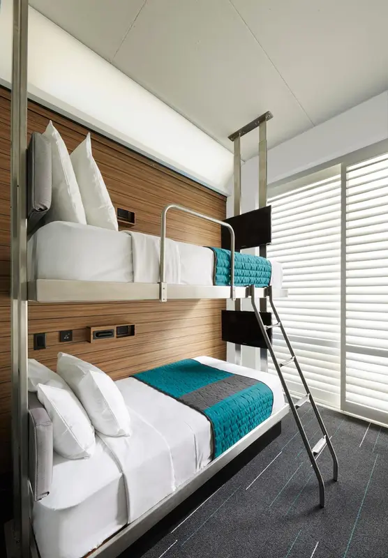 Lit superposé dans une chambre moderne avec une fenêtre à stores.