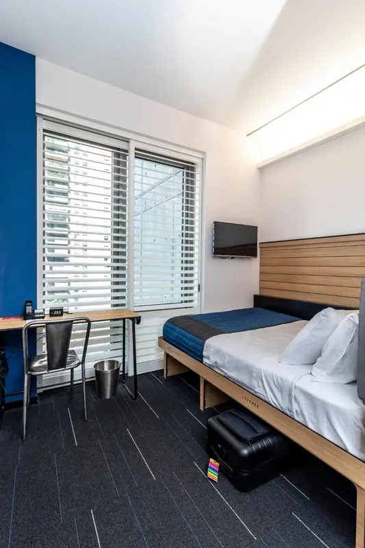 Une chambre moderne avec un lit et un bureau près d'une fenêtre.