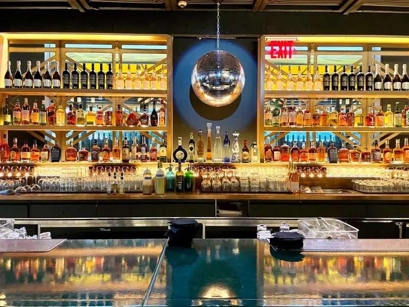 Un comptoir de bar bien garni avec une variété de bouteilles et une boule disco.