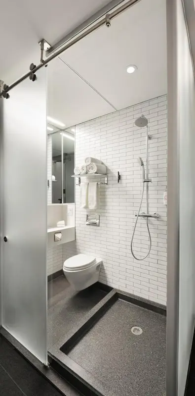 Une salle de bain moderne avec douche à l'italienne et carrelage blanc.