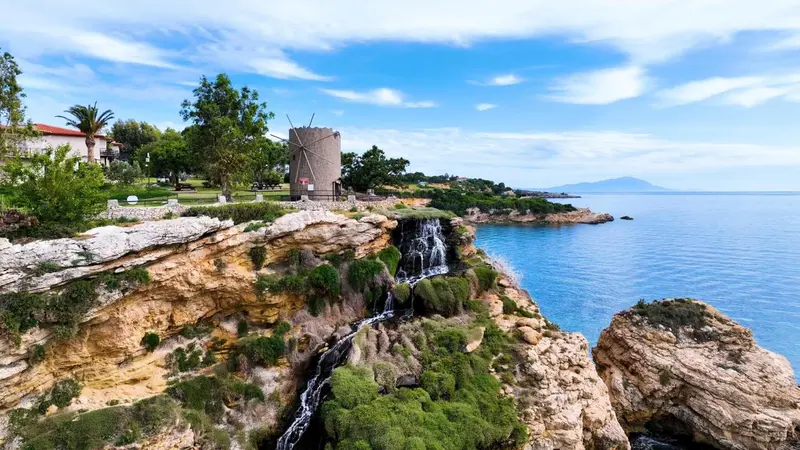 Vue aérienne d'une cascade se jetant dans la mer depuis une falaise rocheuse.
