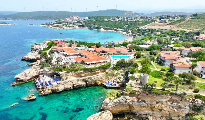 Vue aérienne d'un complexe hôtelier au bord de la mer avec piscine et plage.